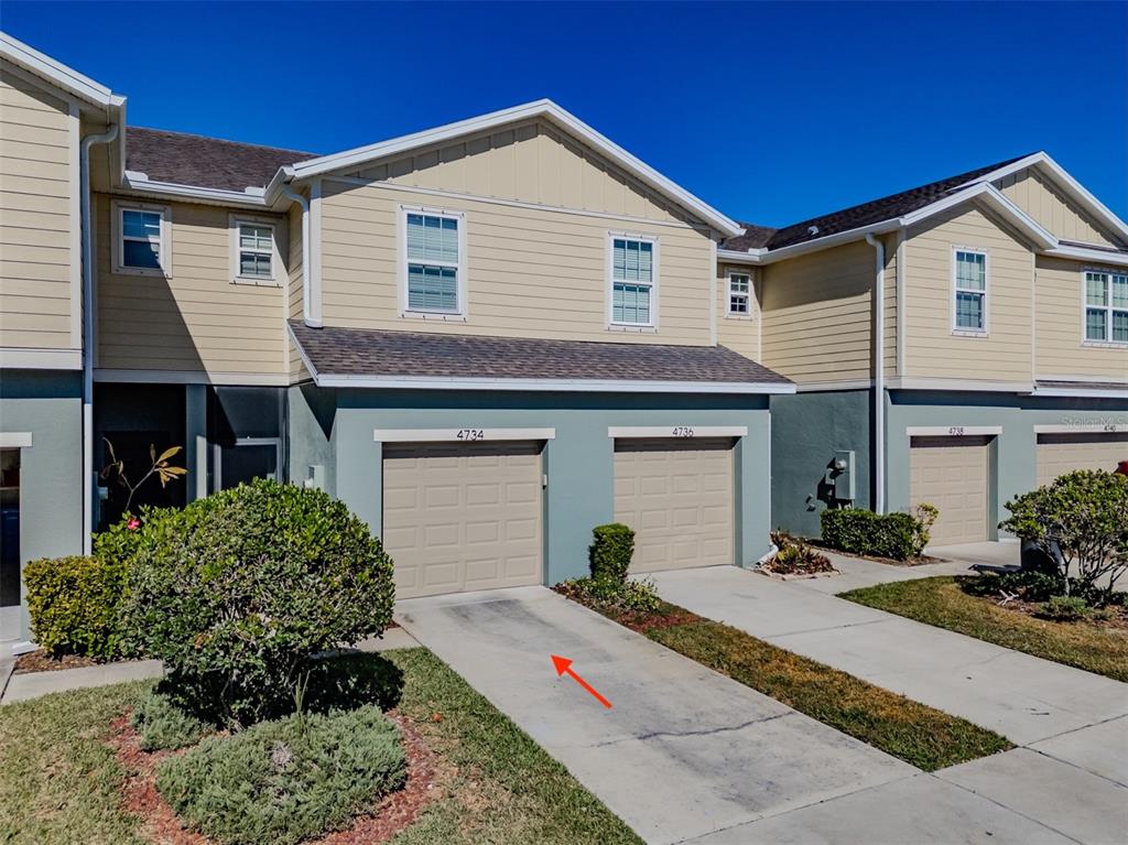 A row of two-story townhomes with beige siding, teal lower levels, and attached garages — 4734 WHITE SANDERLING CT COURT, TAMPA, FL