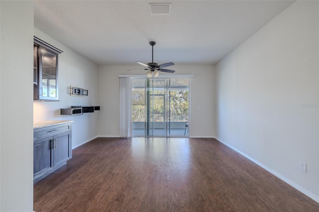A living room features dark wood flooring, a ceiling fan, and a built-in wet bar — 4734 WHITE SANDERLING CT COURT, TAMPA, FL