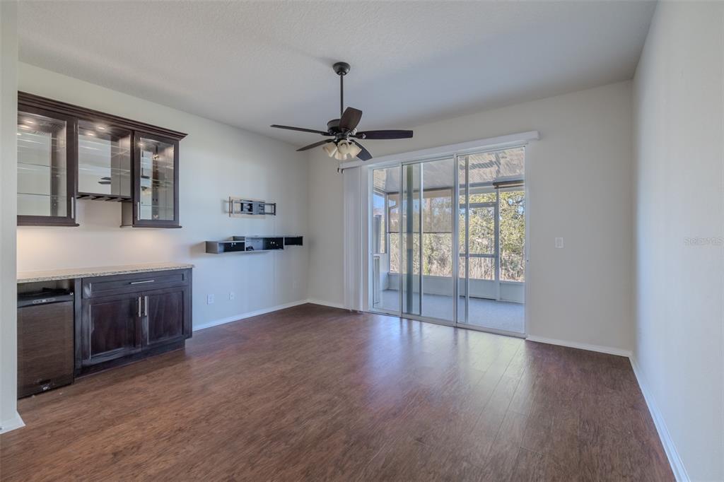 A room with dark wood flooring, a wet bar, a ceiling fan, and sliding glass doors — 4734 WHITE SANDERLING CT COURT, TAMPA, FL