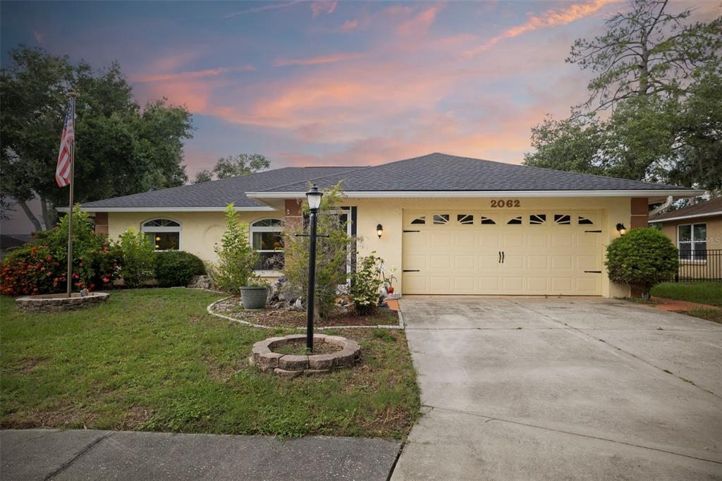 A single-story house with a yellow stucco exterior, a two-car garage, and a front lawn — 2062 OLD ARBOR COURT, SARASOTA, FL