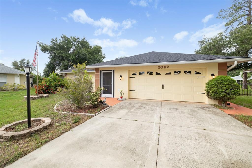A single-story house with a beige exterior, a two-car garage, and a concrete driveway — 2062 OLD ARBOR COURT, SARASOTA, FL