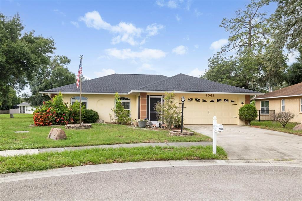 A single-story house with a beige stucco exterior, a dark shingled roof, and a two-car garage — 2062 OLD ARBOR COURT, SARASOTA, FL
