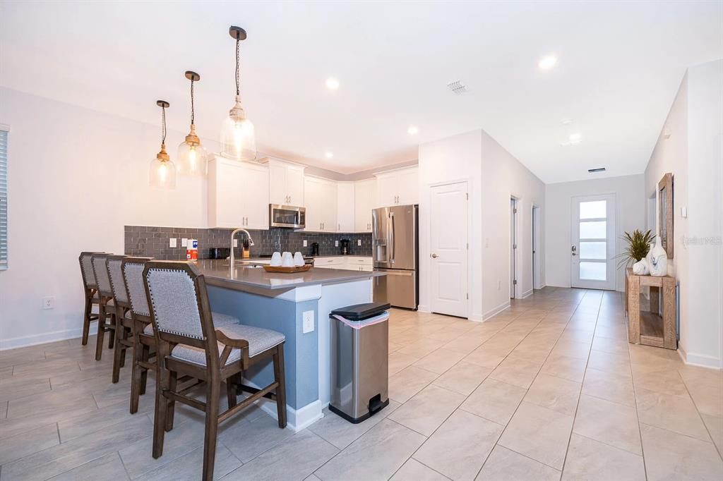A kitchen with white cabinets, stainless steel appliances, a breakfast bar, and tile flooring — 9056 SOMMERSET HILLS DRIVE, DAVENPORT, FL