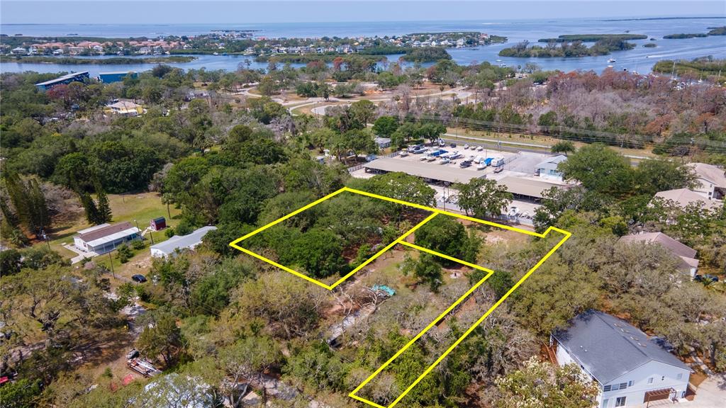 An aerial view shows a wooded lot outlined in yellow near a boat storage facility — 1810, 1814 CEMETERY ROAD, HOLIDAY, FL