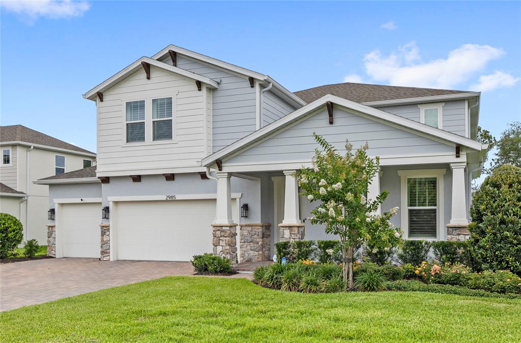 A two-story house with light blue siding, a stone-accented porch, and a three-car garage — 2985 WATER CLOVER COURT, APOPKA, FL