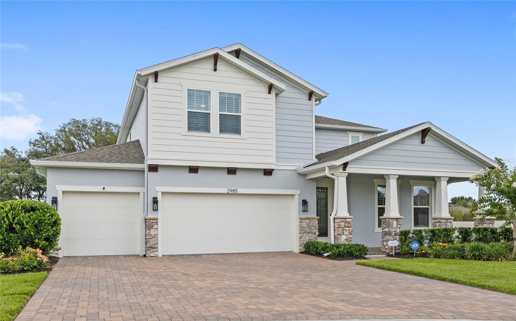 A two-story house features a light blue exterior, stone accents, and a paved driveway — 2985 WATER CLOVER COURT, APOPKA, FL