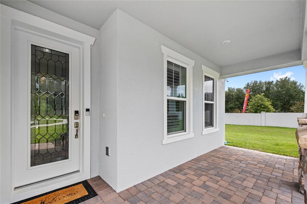A covered porch features a white front door, two windows, and paved flooring — 2985 WATER CLOVER COURT, APOPKA, FL