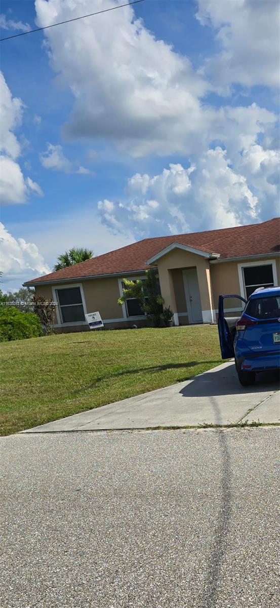 A single-story house with a tan exterior, a red shingled roof, and a blue car parked in the driveway — 466 rewing st, Lehigh Acres FL 33974, LEHIGH ACRES, FL