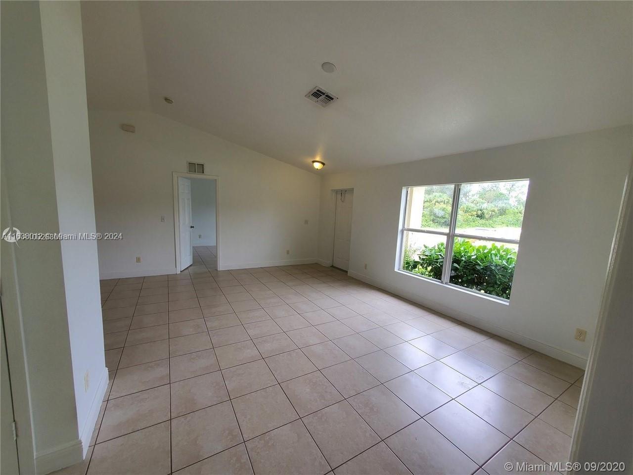 An empty room with beige tile flooring, white walls, and a large window — 466 rewing st, Lehigh Acres FL 33974, LEHIGH ACRES, FL