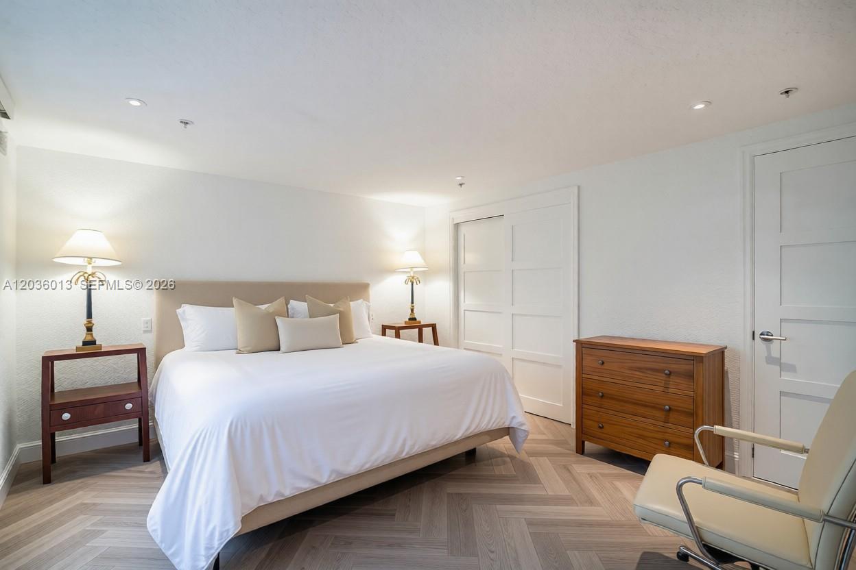 A bedroom features a king bed, wooden nightstands, a dresser, and light-colored herringbone flooring — 322 Buchanan St # 0, Hollywood FL 33019, HOLLYWOOD, FL