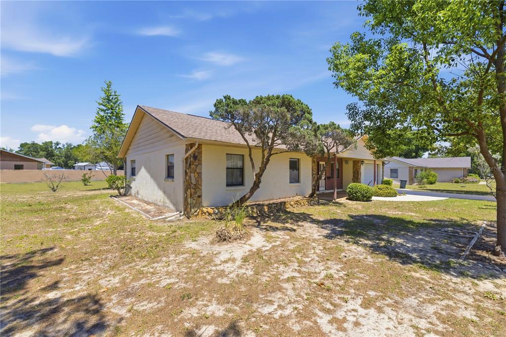 A single-story house with a stone-accented exterior and a large, sandy front yard — 3051 SW 98TH STREET ROAD, OCALA, FL