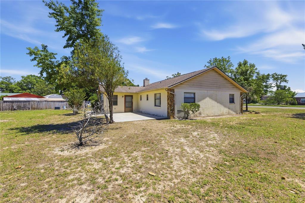A single-story house with a concrete patio and stone accents sits on a grassy lot — 3051 SW 98TH STREET ROAD, OCALA, FL