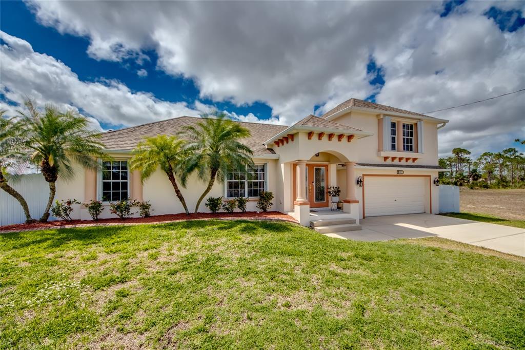 A single-story house with a two-story section, a garage, and palm trees in the front — 2012 NE 33RD LANE, CAPE CORAL, FL
