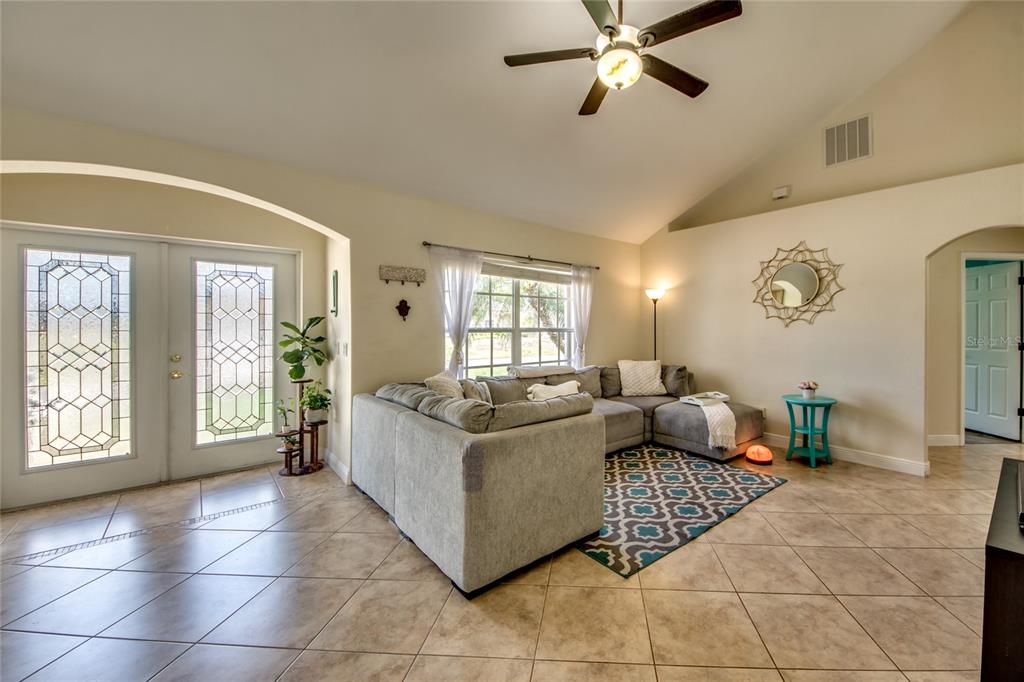 A living room features a gray sectional sofa, a patterned rug, and double glass doors — 2012 NE 33RD LANE, CAPE CORAL, FL