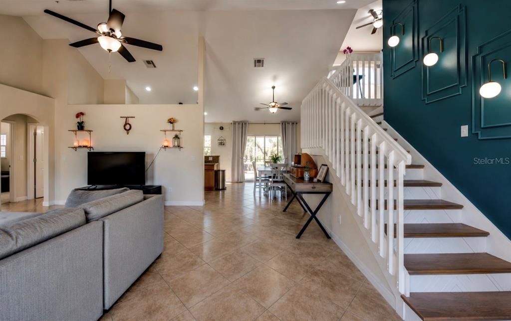 A living room features tile floors, a staircase with a teal accent wall, and ceiling fans — 2012 NE 33RD LANE, CAPE CORAL, FL
