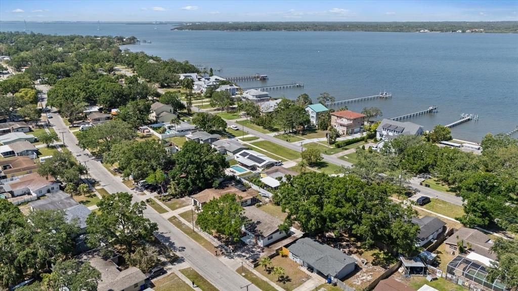 An aerial view shows a residential neighborhood with houses, trees, and docks along a bay — 324 COUNTRY CLUB DRIVE, OLDSMAR, FL
