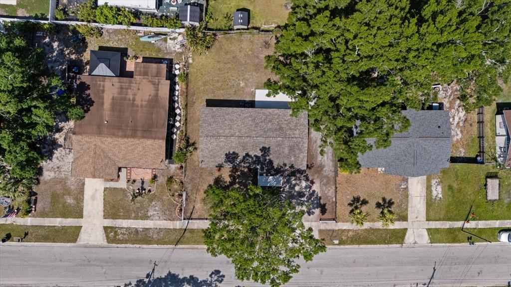 An aerial view shows three residential houses with yards and trees along a paved street — 324 COUNTRY CLUB DRIVE, OLDSMAR, FL