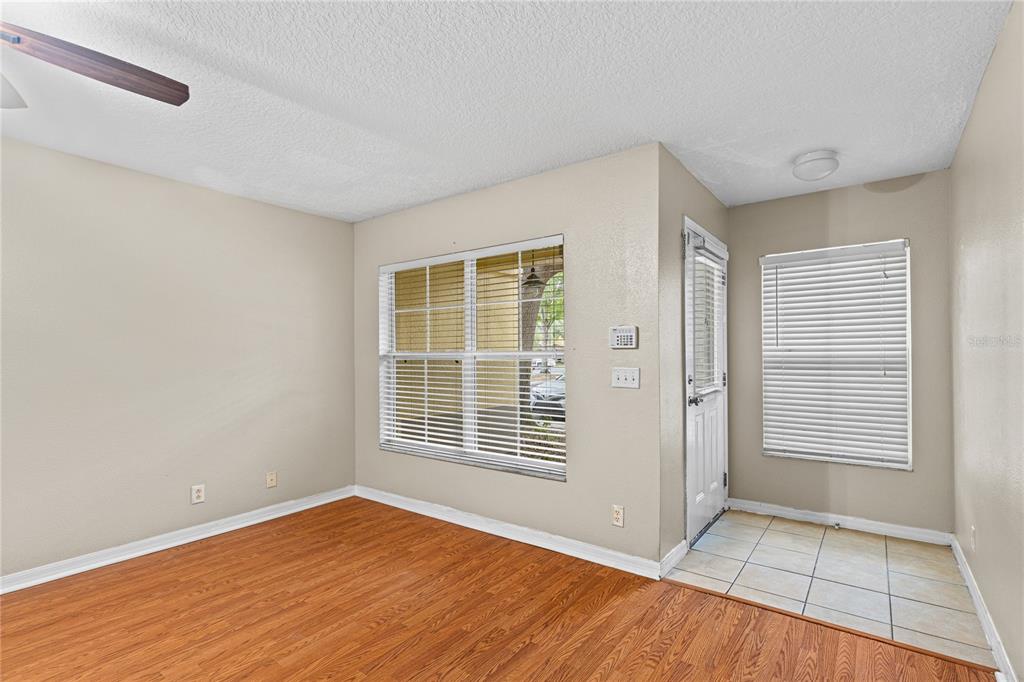 An empty room features wood-look flooring, a tiled entryway, and two windows with blinds — 216 DRAGONS FIRE PLACE, VALRICO, FL