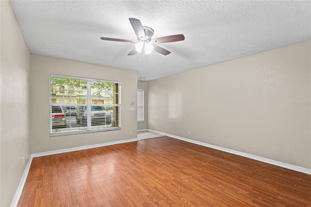 An empty room features wood-look flooring, a ceiling fan, and a window overlooking a parking lot — 216 DRAGONS FIRE PLACE, VALRICO, FL