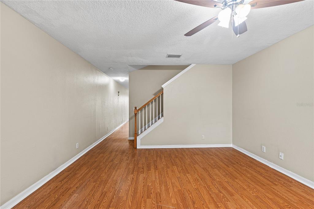 An empty room with wood-look flooring, a ceiling fan, and a staircase with wooden railings — 216 DRAGONS FIRE PLACE, VALRICO, FL