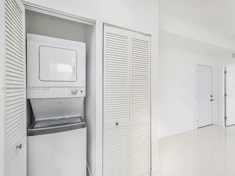 A stacked washer and dryer unit sits inside a closet with white louvered doors — 676 NW 47th St # 7, Miami FL 33127, MIAMI, FL