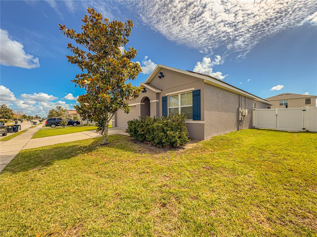 A single-story house with a gray stucco exterior, blue shutters, and a front lawn — 1742 VAN GOGH DRIVE, AUBURNDALE, FL