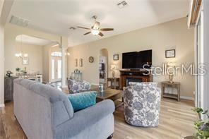 A living room features a gray sofa, a patterned armchair, and a wall-mounted television — 17951 SE 115TH CIRCLE, SUMMERFIELD, FL