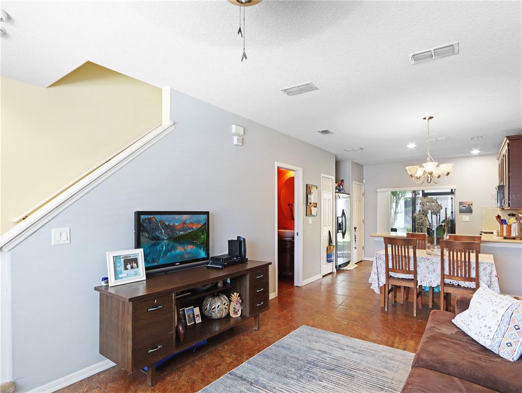 A living room with a television console, stairs, and an adjacent dining area with tile floors — 3250 WINDLESHORE, SANFORD, FL