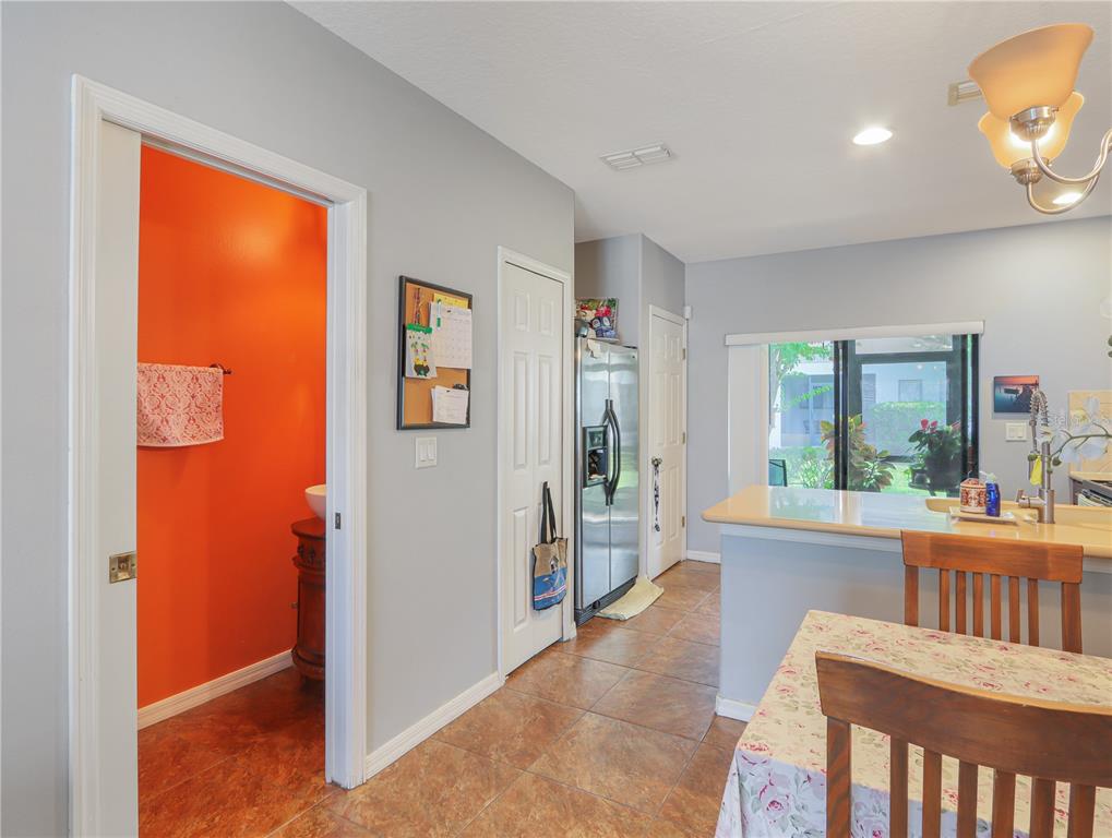 A view of a dining area and kitchen with tile floors and an orange bathroom — 3250 WINDLESHORE, SANFORD, FL