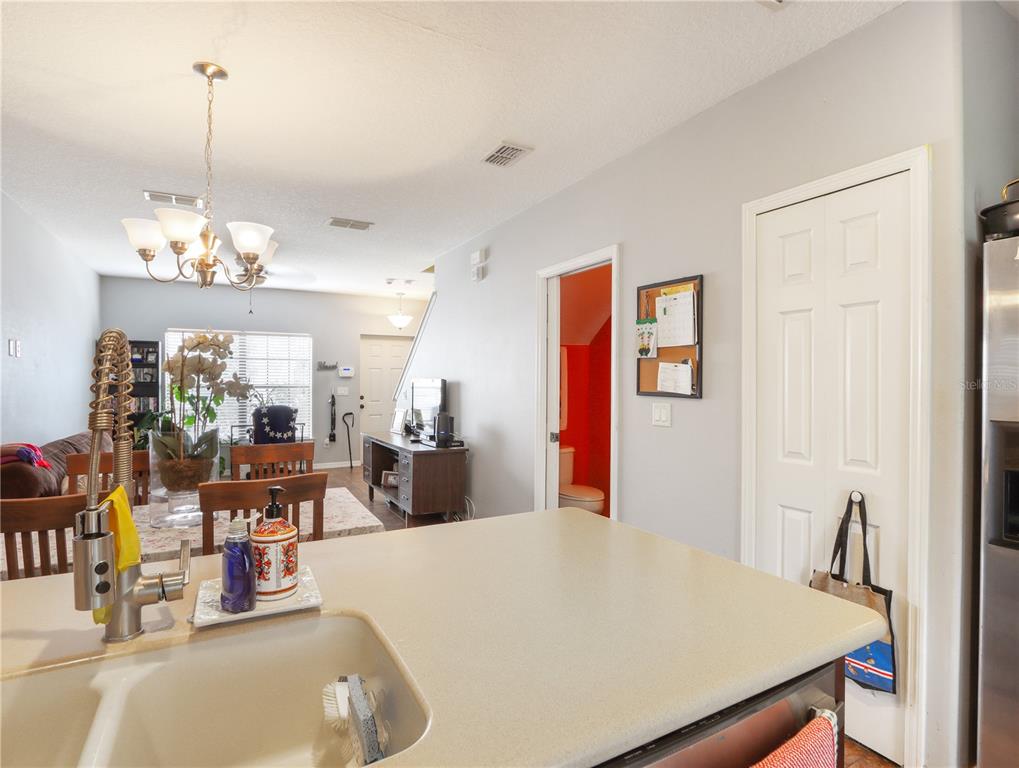 A kitchen island with a sink overlooks a dining area and living room — 3250 WINDLESHORE, SANFORD, FL