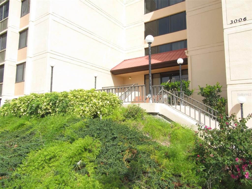 The exterior of a multi-story building features a staircase leading to a covered entrance — 3006 CARING WAY UNIT 422, PORT CHARLOTTE, FL