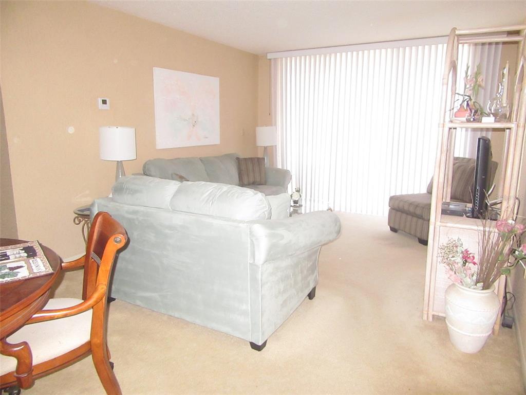 A living room features a light blue sofa, a dining chair, and a shelving unit — 3006 CARING WAY UNIT 422, PORT CHARLOTTE, FL
