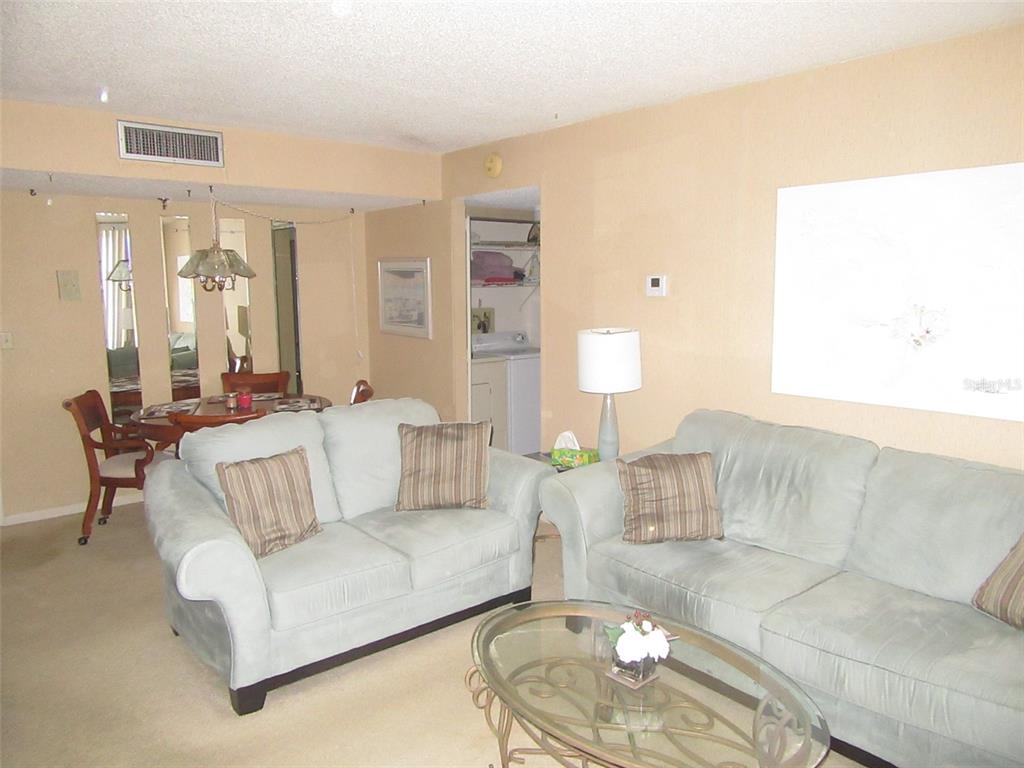 A living room features two light-colored sofas, a glass coffee table, and a dining area — 3006 CARING WAY UNIT 422, PORT CHARLOTTE, FL