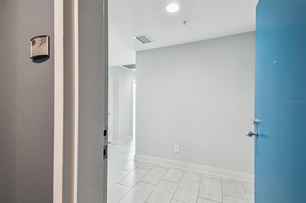 An open doorway reveals a tiled entryway leading to a hallway with light gray walls — 1208 E KENNEDY BOULEVARD UNIT 1115, TAMPA, FL