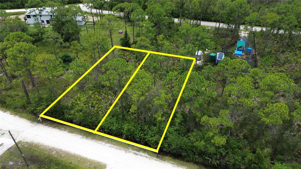 An aerial view shows two adjacent, wooded, undeveloped lots outlined in yellow along a dirt road — 28381 HERMOSO DRIVE, PUNTA GORDA, FL