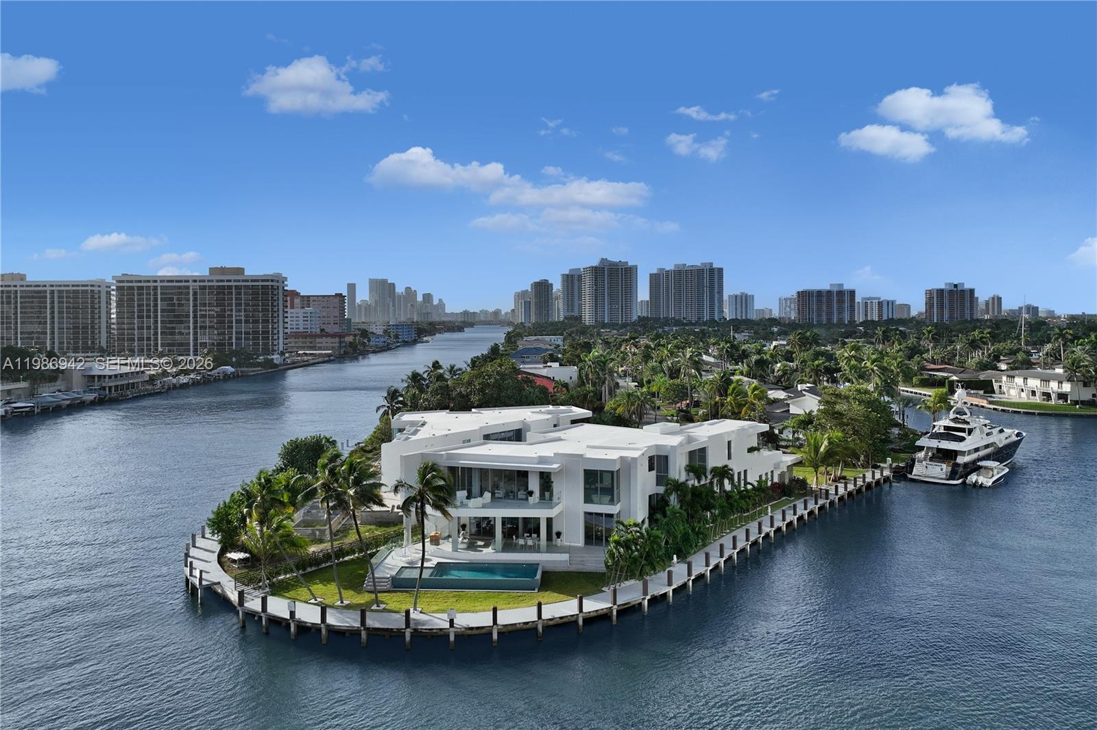 An aerial view shows a modern white waterfront mansion with a pool on a peninsula — 501 Palm Dr, Hallandale Beach FL 33009, HALLANDALE BEACH, FL