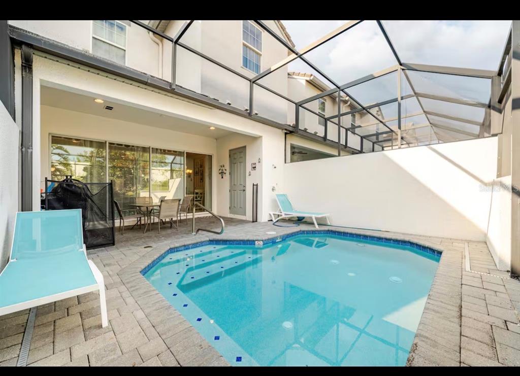 A small swimming pool with a screened-in patio and lounge chairs in a backyard — 354 CAPTIVA DRIVE, DAVENPORT, FL
