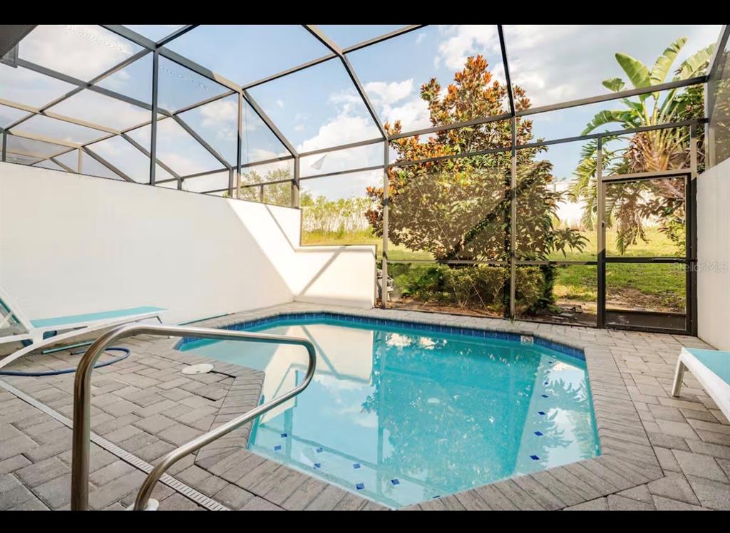 A screened-in patio features a small swimming pool surrounded by gray brick pavers — 354 CAPTIVA DRIVE, DAVENPORT, FL