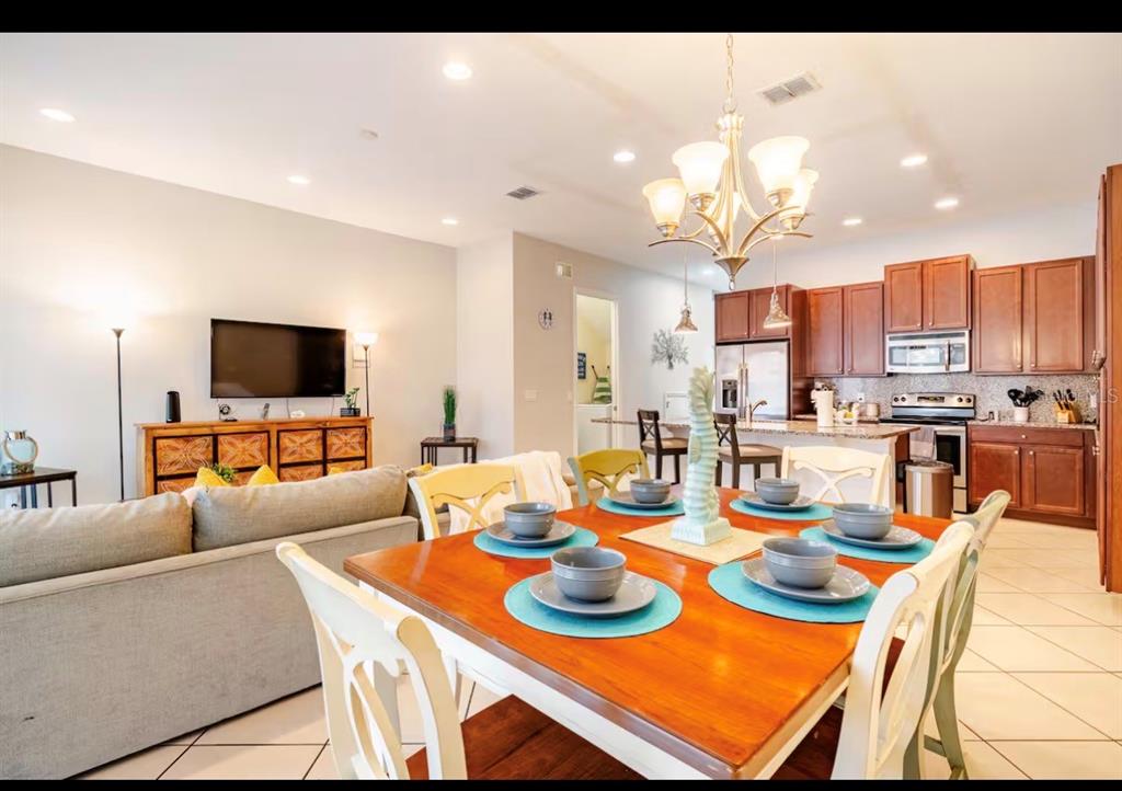 A dining area with a wooden table sits in front of an open kitchen and living room — 354 CAPTIVA DRIVE, DAVENPORT, FL