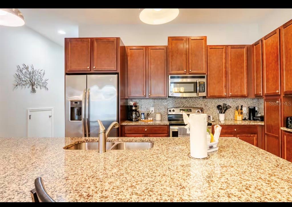 A kitchen features granite countertops, wooden cabinets, stainless steel appliances, and a large island — 354 CAPTIVA DRIVE, DAVENPORT, FL