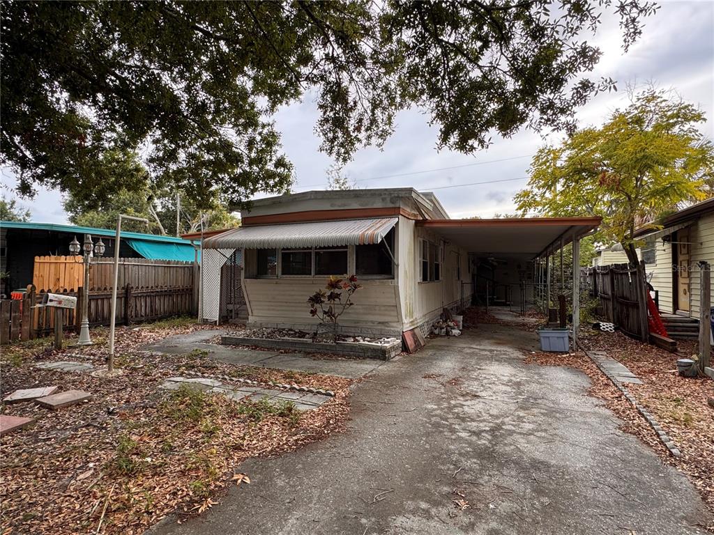An exterior view of a single-wide mobile home with a carport and a concrete driveway — 5042 76TH STREET N, ST PETERSBURG, FL