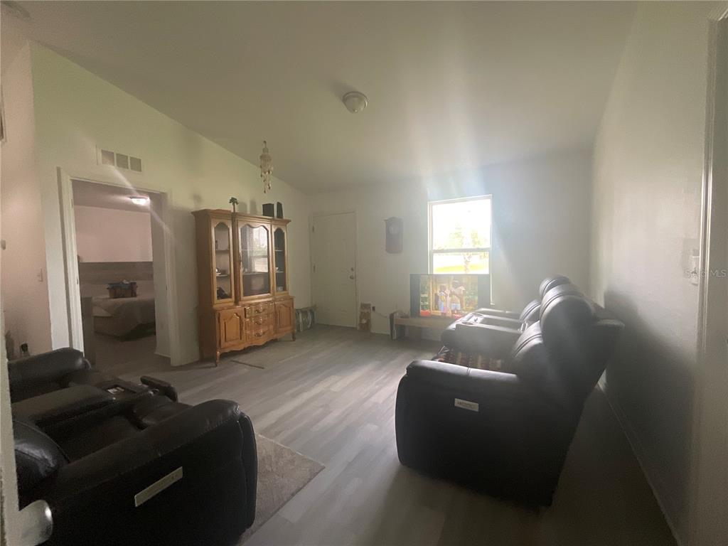 A living room features light wood-look flooring, two dark leather recliners, and a wooden hutch — 15309 SW 52ND CIRCLE, OCALA, FL