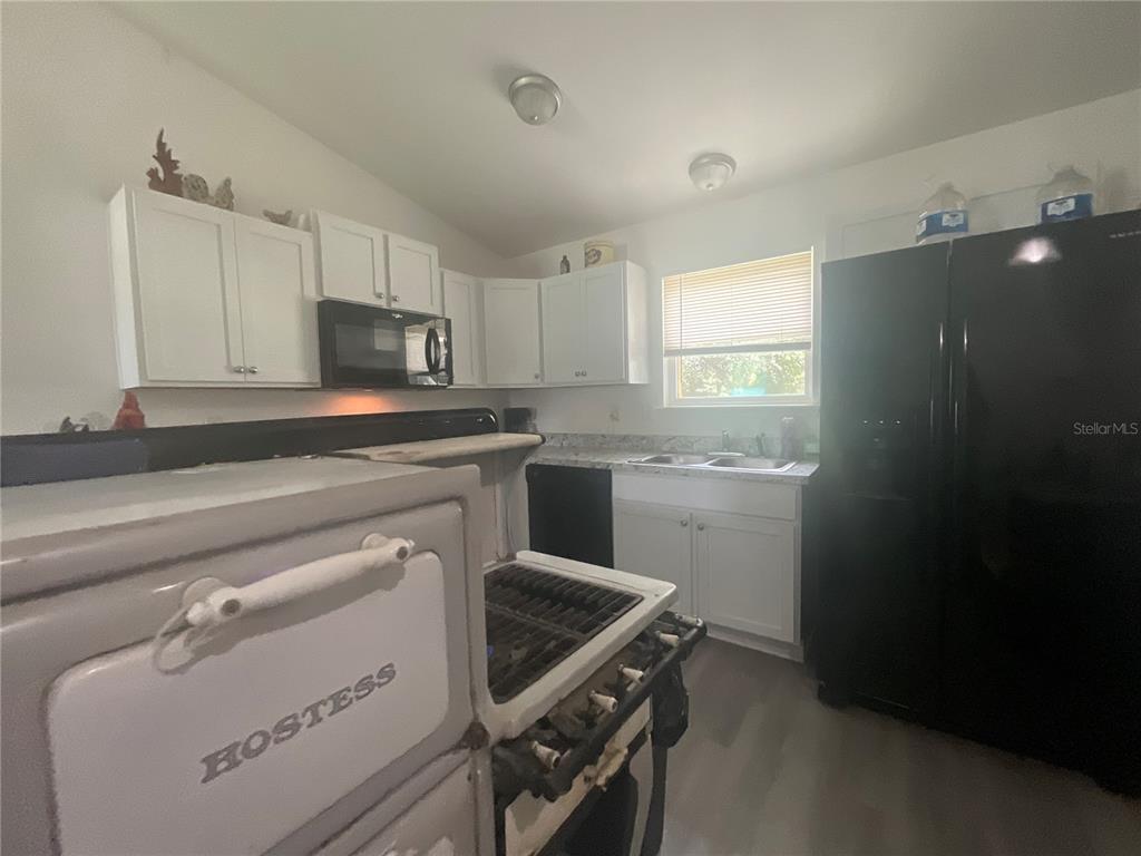 A kitchen features white cabinets, black appliances, a double sink, and a vintage Hostess stove — 15309 SW 52ND CIRCLE, OCALA, FL