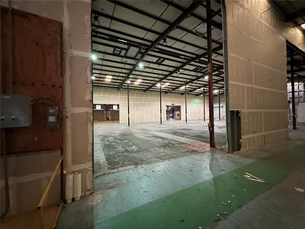 An expansive, unfinished warehouse interior features exposed metal ceiling trusses and unfinished drywall walls — 5407 NW 44TH AVENUE, OCALA, FL