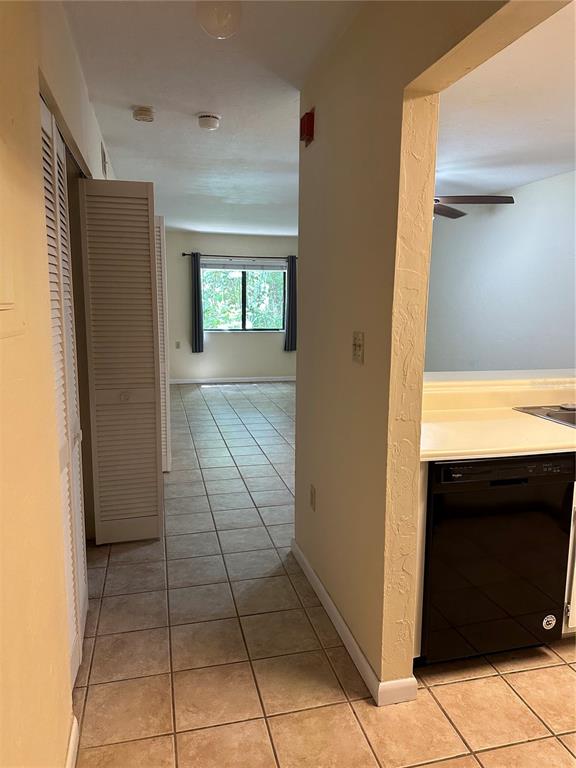 A tiled hallway leads to a living area with a window, adjacent to a kitchen — 83 SE 16TH AVENUE UNIT E102, GAINESVILLE, FL