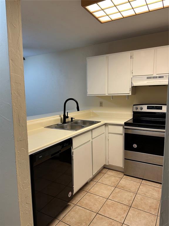 A kitchen features white cabinets, stainless steel appliances, a black faucet, and tiled flooring — 83 SE 16TH AVENUE UNIT E102, GAINESVILLE, FL