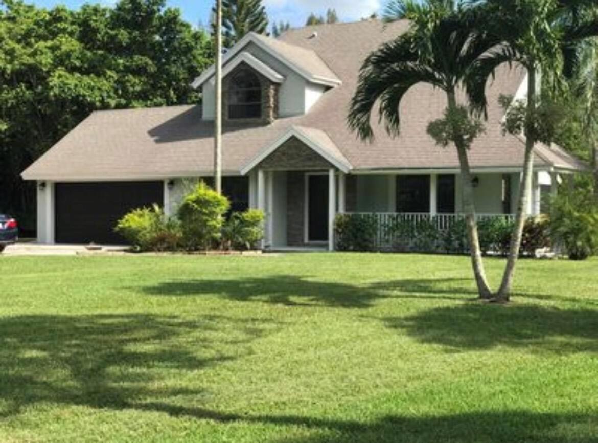 A two-story house with a brown shingled roof, stone accents, and a large front lawn — 11852 61st Street N, FL 33412, FL