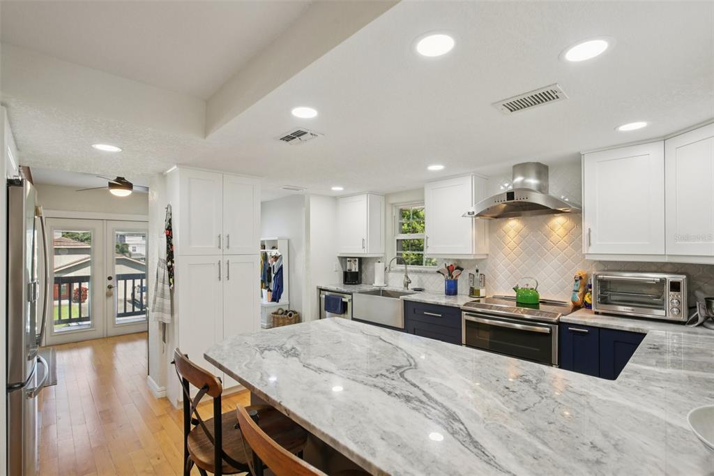 A kitchen features white upper cabinets, dark blue lower cabinets, and a marble-topped island — 3140 N CANAL DRIVE, PALM HARBOR, FL