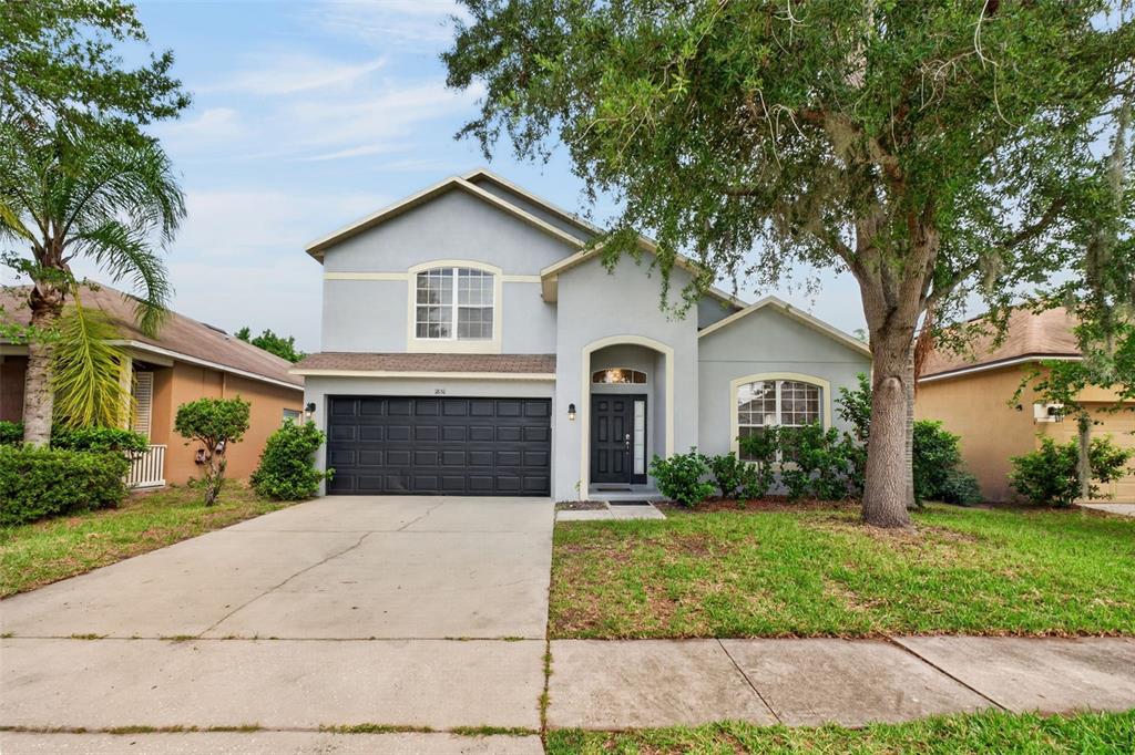 A two-story house with a light blue exterior, a dark garage door, and a front lawn — 1851 GREAT FALLS WAY, ORLANDO, FL
