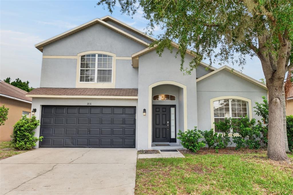 A two-story house with a gray stucco exterior, a dark garage door, and a front entrance — 1851 GREAT FALLS WAY, ORLANDO, FL